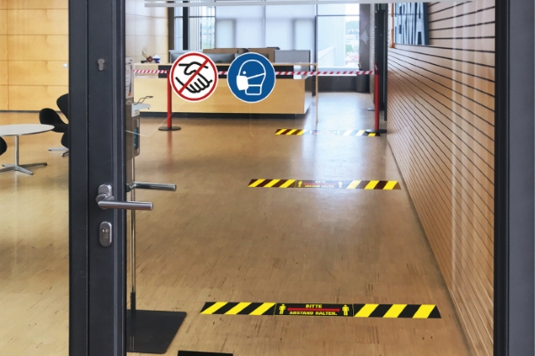 Door with signs and floor stickers to maintain distance
