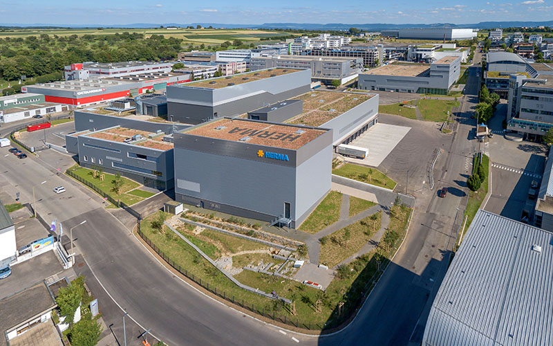 Modern industrial buildings with green roofs and adjacent streets in a commercial area.