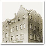 Historic building with a brick facade and gabled roof, several windows visible, depicted in sepia tones.