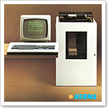 A computer with a monitor and keyboard is next to a white device that looks like a printer or scanner.