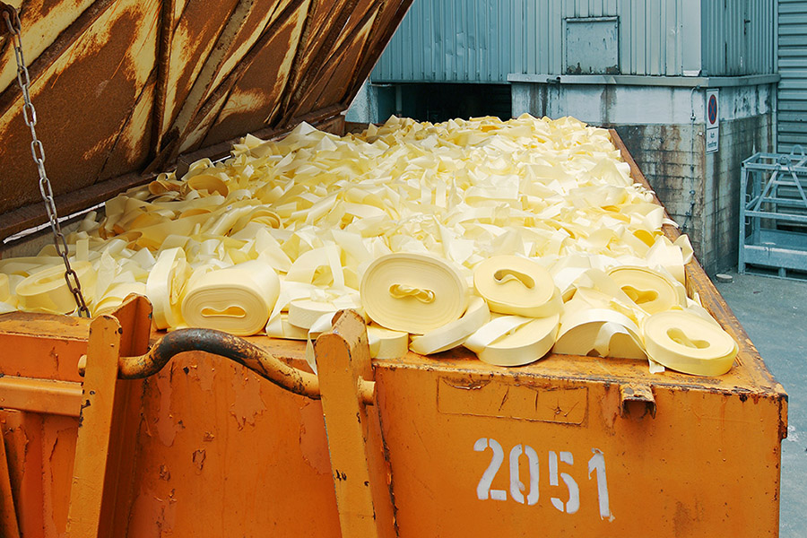 A container full of yellow plastic scraps, stacked in various shapes and sizes.