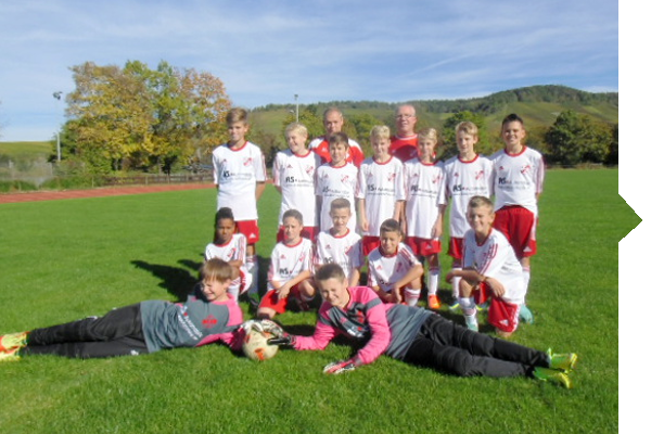 A youth soccer team poses on a grass field, dressed in white and red jerseys, with a ball in the foreground.