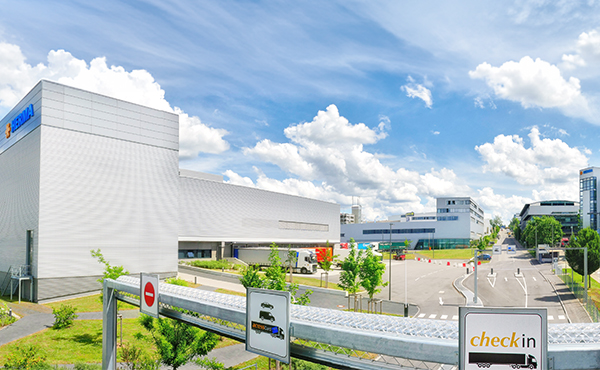 Modern buildings with clean lines against a blue sky. Traffic signs point towards check-in and other directions.