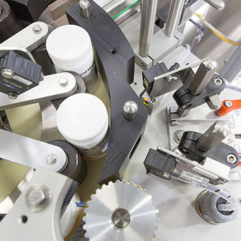 Machine for labeling bottles, equipped with various mechanical components and sensors for precise handling.