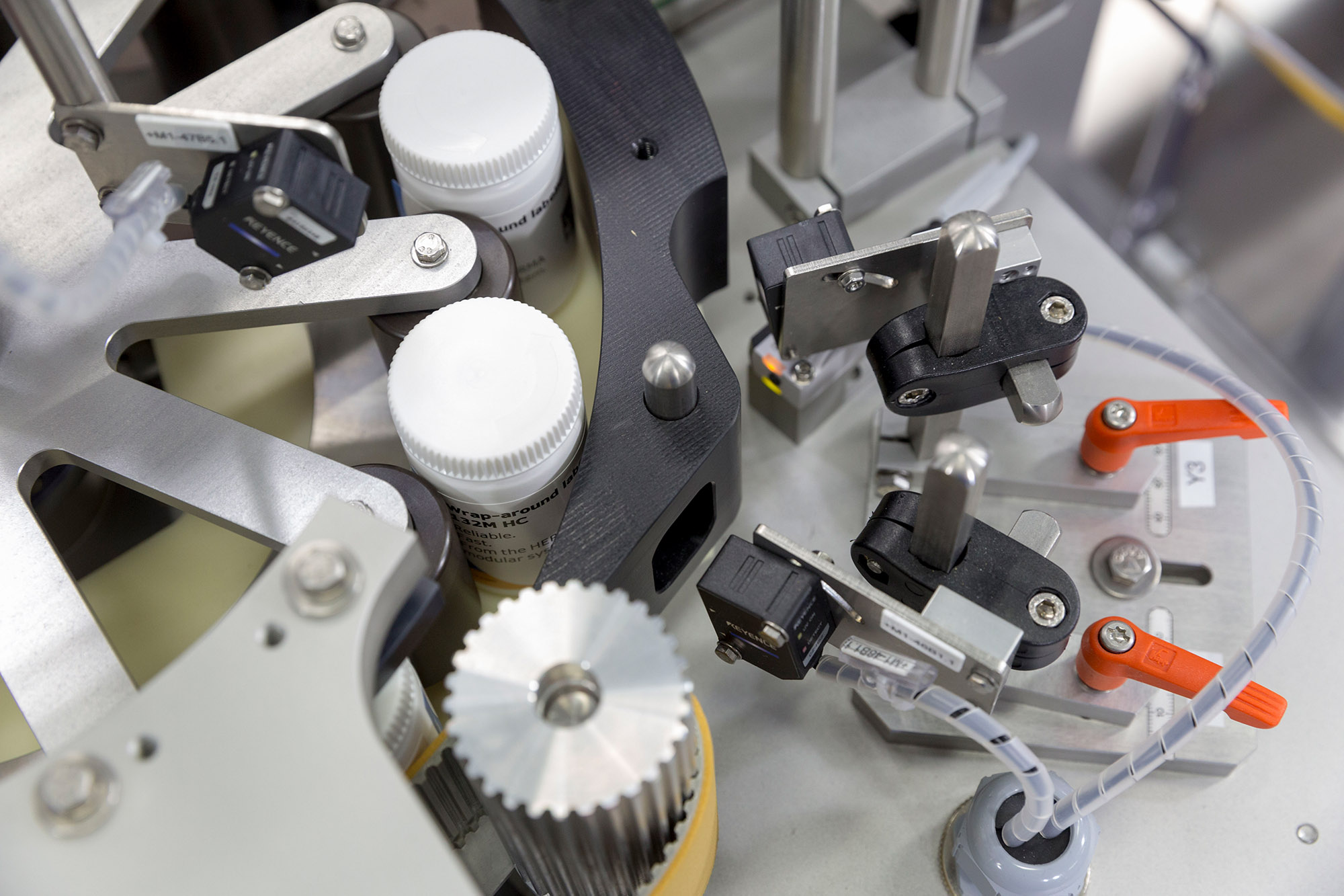 Machine parts for bottling, including sensors and mechanisms to control the process.