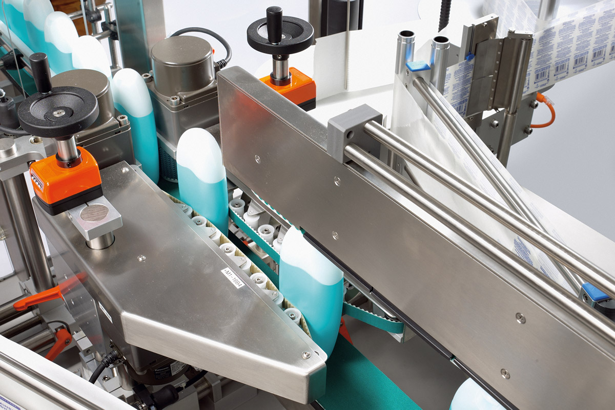 A production line with bottles being transported on a conveyor belt. Machine components are visible that support the filling process.