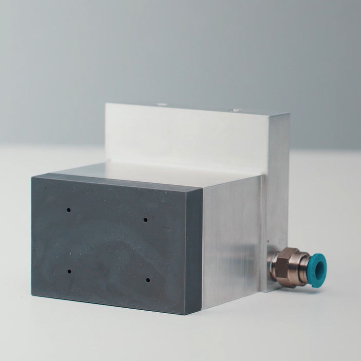 A rectangular device with a metallic surface and a black plastic block, equipped with a connector.