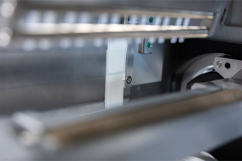 A view of the internal parts of a machine featuring metallic components and a white element positioned within a mechanical system.