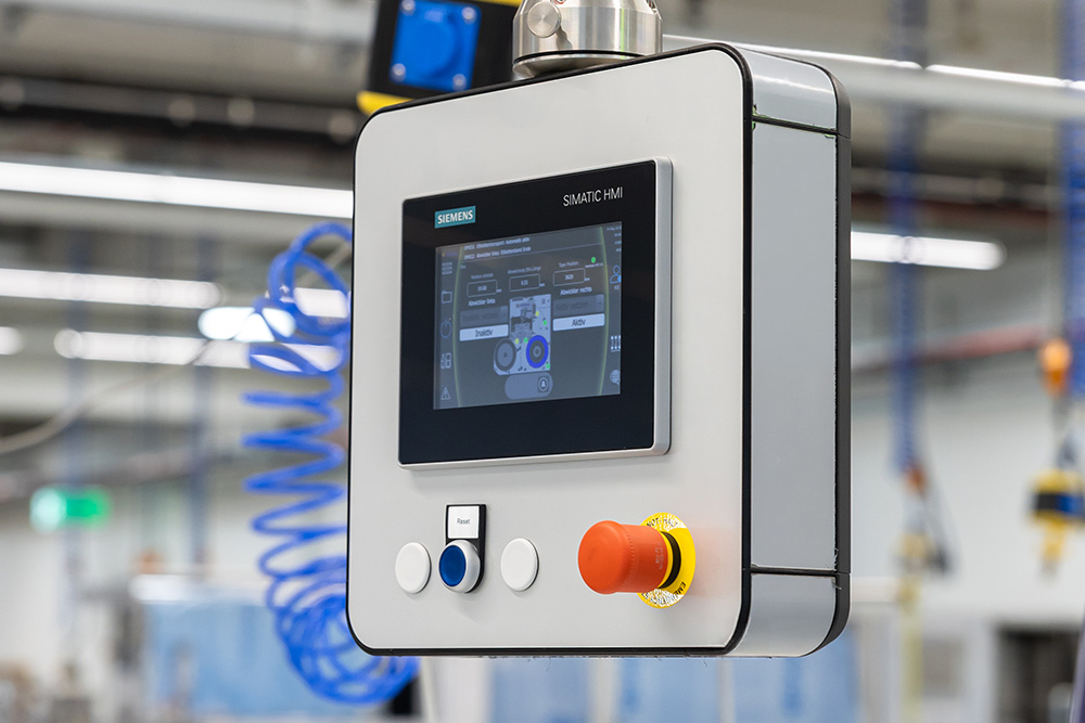 Control panel with a touchscreen and control buttons, used for operating machines in an industrial environment.
