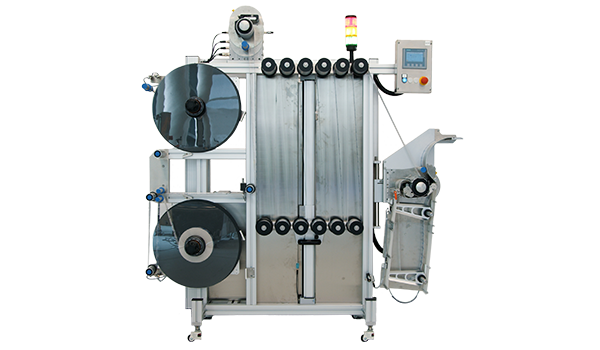 An industrial packaging machine with two large rolls, a control unit, and a discharge area for packaged products.