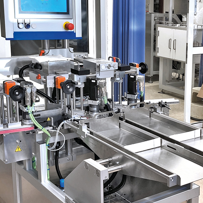 Automated machine arrangement with multiple robotic arms and a control unit, designed for industrial manufacturing processes.