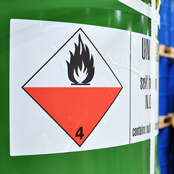 Hazardous materials label on a green steel drum