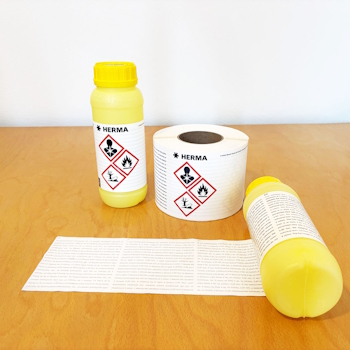 Two yellow bottles with hazard symbols and a roll label on a table. The bottles likely contain chemical substances.