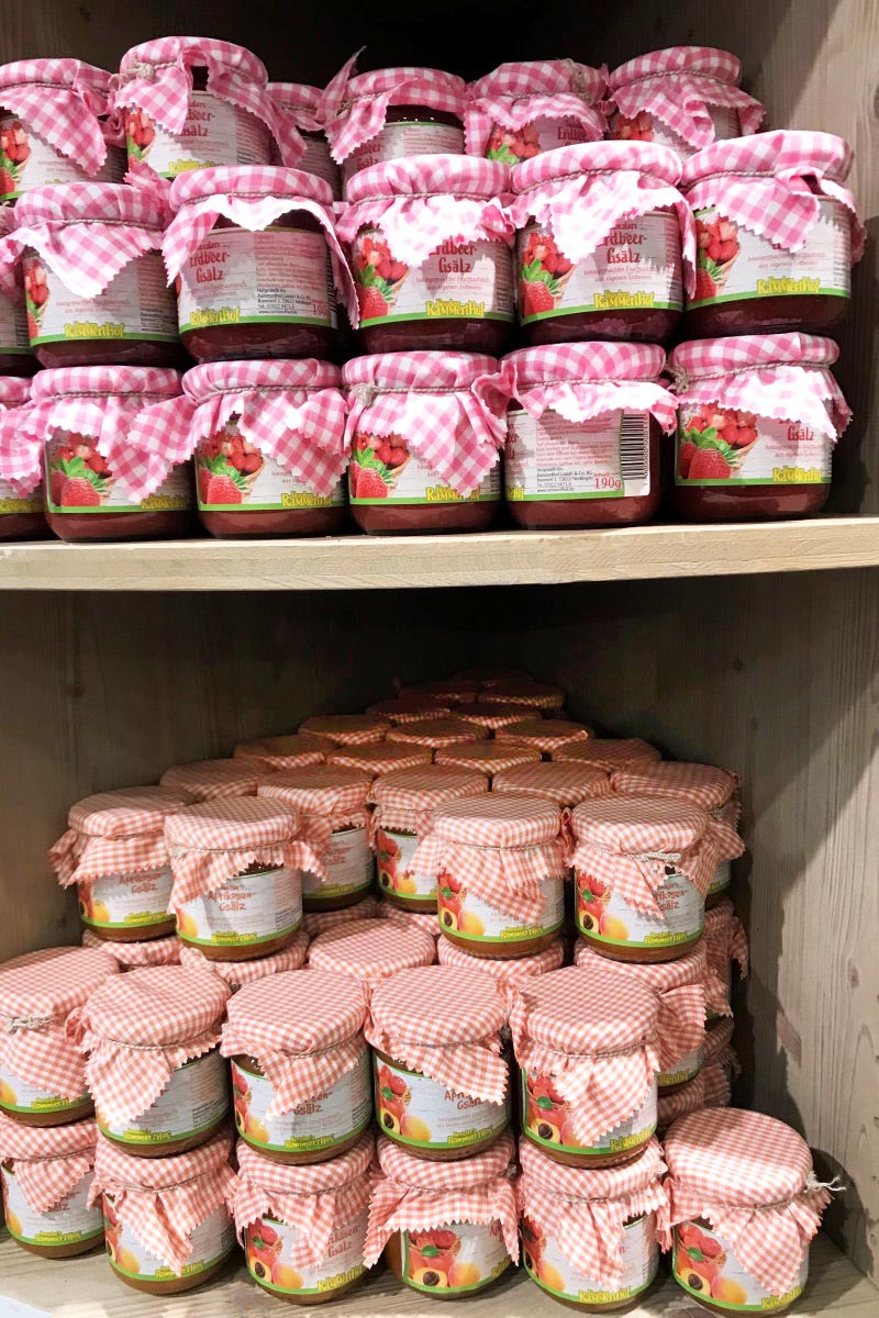 Order roll labels online in digital printing: jam labels on jars with fruit spreads, many jars on the shelf.