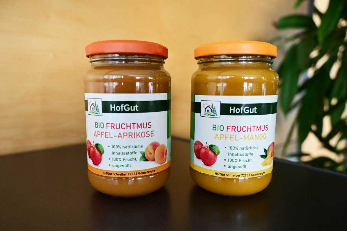 Order roll labels online in digital printing: glass labels for organic fruit puree, 2 jars, wooden background.