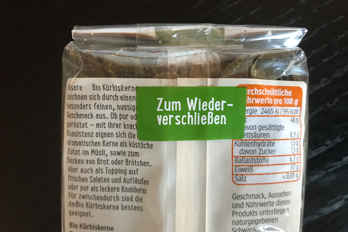 Sealing Labels: transparent resealable label with a colored pull tab, on a pouch packaging with pumpkin seeds.