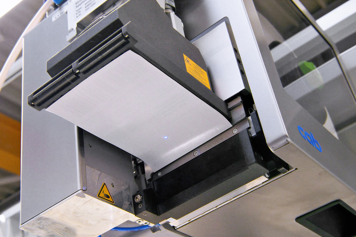 Linerless label HERMA InNo-Liner in cab Print&Apply system, ready to be applied to the shipping carton.