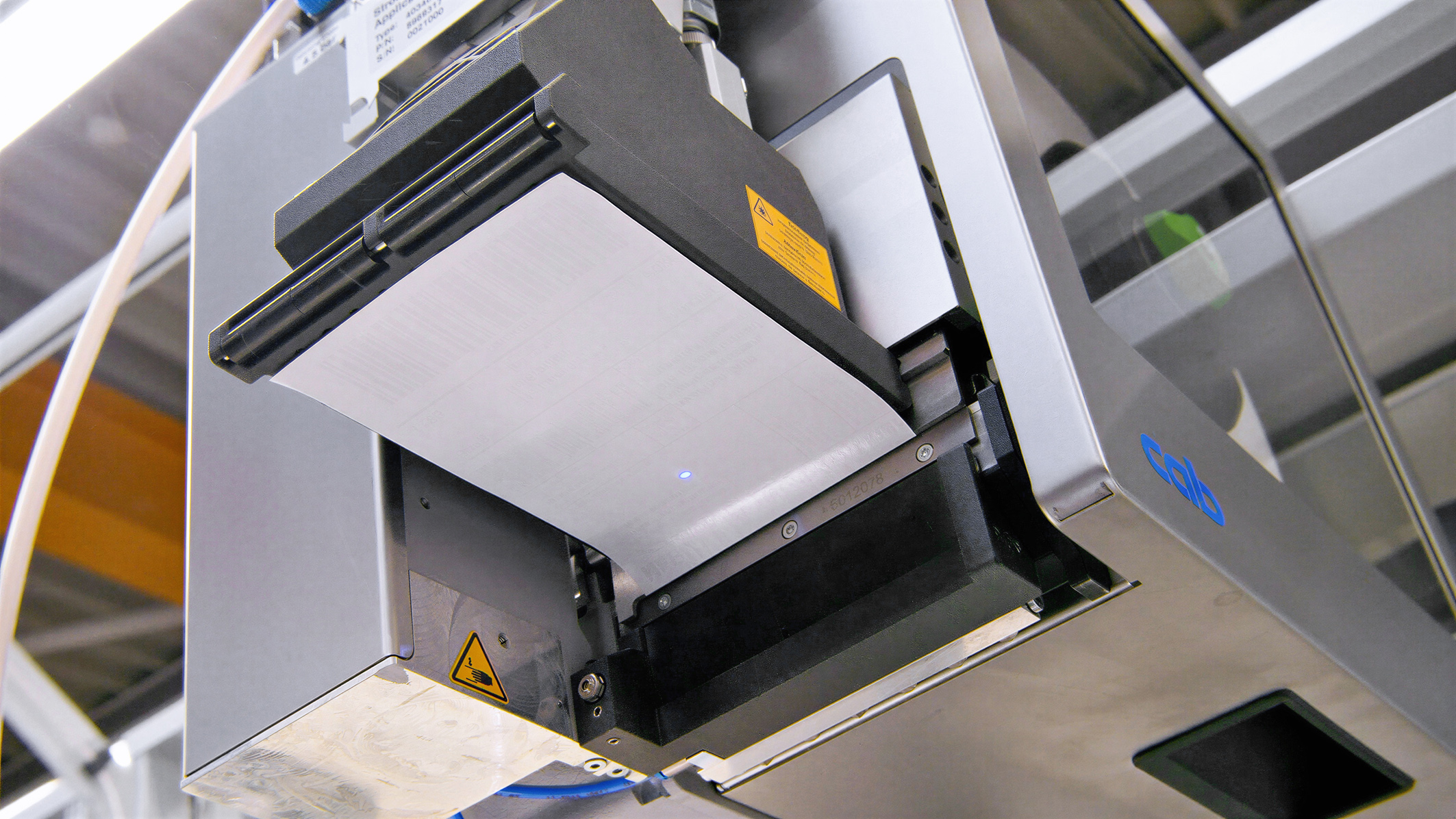 A printer with an empty print cartridge, ready to print. The machine displays technical components and safety labels.