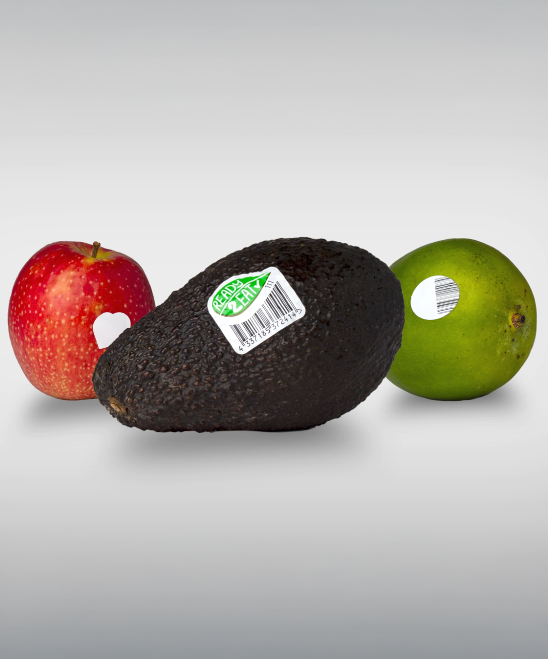A black avocado with a price tag, flanked by a red apple and a green lime.