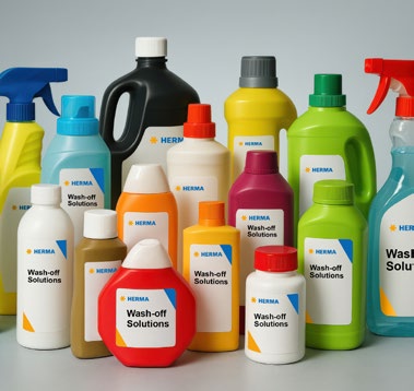 Various bottles and containers with cleaning agents, labeled 'Wash-off Solutions' and featuring the HERMA logo.