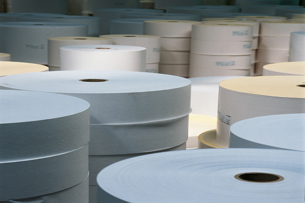 Rolls of paper in various sizes and colors, stacked in a storage room.