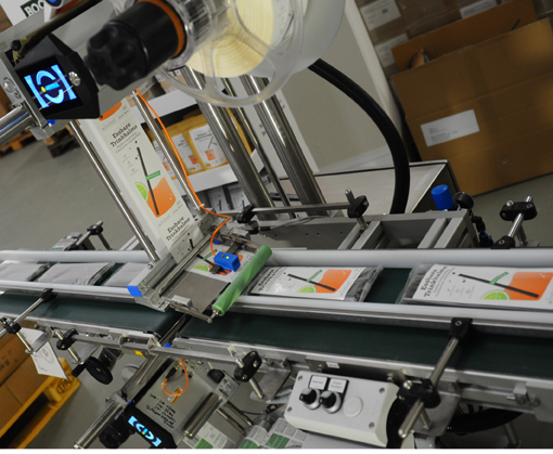 A production line with a conveyor belt, where products are moved with labels and a scanner for quality control.