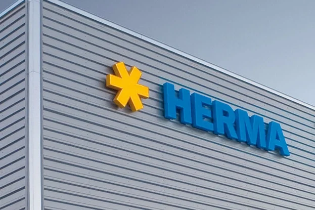 Facade of a modern building featuring the logo 'HERMA' in blue lettering and a yellow symbol.