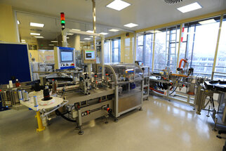 Modern production facility with machines for processing and packaging, equipped with monitors and various tools.