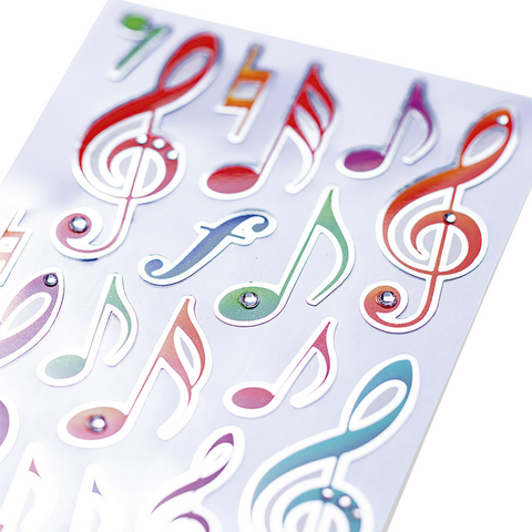 Bunte Musiknoten und Symbole auf einem weißen Hintergrund, einige mit Glitzersteinen verziert.