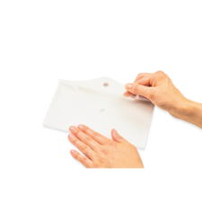 Eine Hand hält ein weißes Blatt Papier, während die andere Hand es sanft auf eine flache Oberfläche drückt.