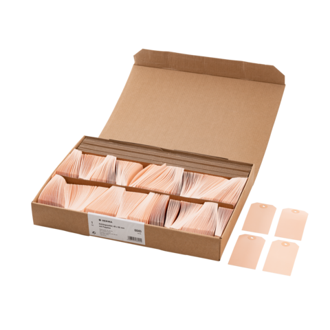 Ein Karton mit mehreren Stapeln von beige-farbenen Etiketten, einige Etiketten liegen daneben.