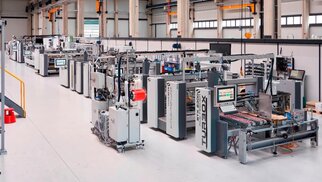 A modern production hall equipped with several machines and systems designed for the manufacturing and assembly of components.