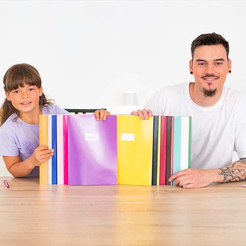 Ein Mann und ein Mädchen sitzen an einem Tisch, lächeln und halten bunte Ordner in der Hand.