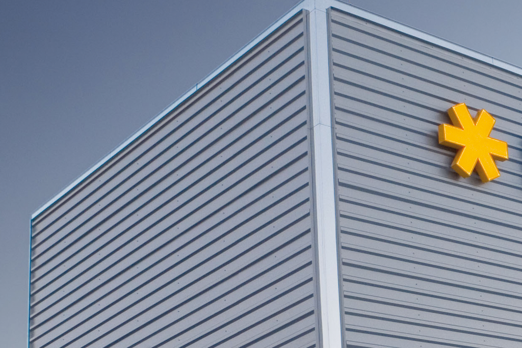 Facade of a modern building featuring the HERMA logo in blue lettering and a yellow symbol.