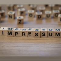 Wooden letters spell out the word "IMPRINT" on a table, surrounded by additional letters.