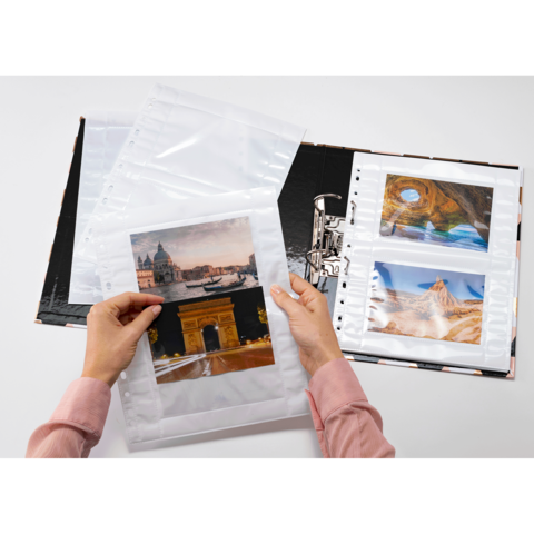 Eine Person hält Fotos in Klarsichthüllen und blättert durch ein Fotoalbum mit verschiedenen Landschaftsaufnahmen.