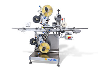 Automatic labeling machine with two labeling heads, equipped with rollers and control elements, on a sturdy frame.