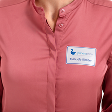 Ein Namensschild auf einer blauen Bluse zeigt den Namen "Linda Miller" und die Position "Marketing" für die Agentur "Print Media".