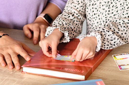 Desk with a book that is covered in protective book wrapping.
