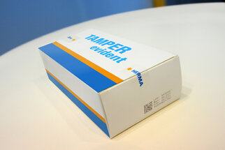 Packaging labeled 'TAMPER evident' with a blue and orange stripe, produced by HERMA.