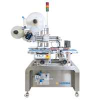 Automatische Etikettiermaschine mit zwei Rollen, Steuerungseinheit und einem stabilen Edelstahlrahmen. Marke: HERMA.