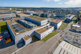 Aerial view of an industrial area featuring several modern buildings, green roofs, and adjacent streets.