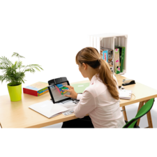 Eine Frau sitzt an einem Schreibtisch und nutzt ein Tablet, um auf einem Dokument zu arbeiten. Im Hintergrund sind Bücher und eine Pflanze sichtbar.