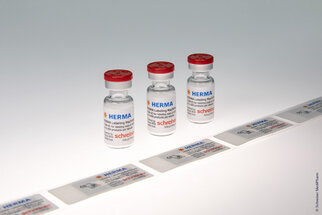 Three vials of vaccine with labels that provide information on usage and origin.