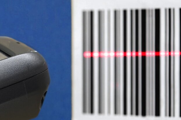 Hand with scanner scanning a barcode label, landscape format.