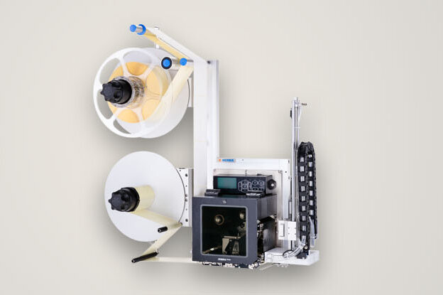 A device with two coils, a pressure mechanism, and various control elements, used for processing paper or labels.