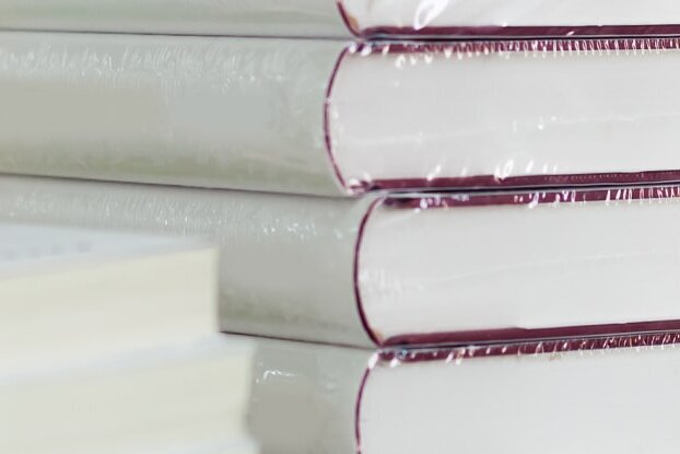 Books shrink-wrapped in stacks, image motif for book labeling with removable labels from HERMA, landscape format.