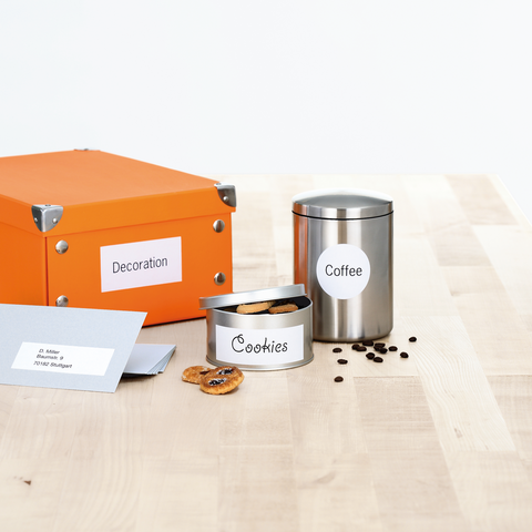 Orange box with the label 'Decoration', silver coffee pot, and a tin labeled 'Cookies', surrounded by coffee beans.