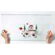 Eine transparente Glasplatte wird von zwei Händen gehalten, mit festlichen Motiven wie einem Weihnachtsmann, Tannenbäumen und Geschenken.