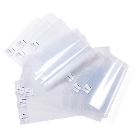 Eine Sammlung transparenter Kunststoffhüllen in verschiedenen Größen, teilweise mit Etiketten, auf einem weißen Hintergrund.